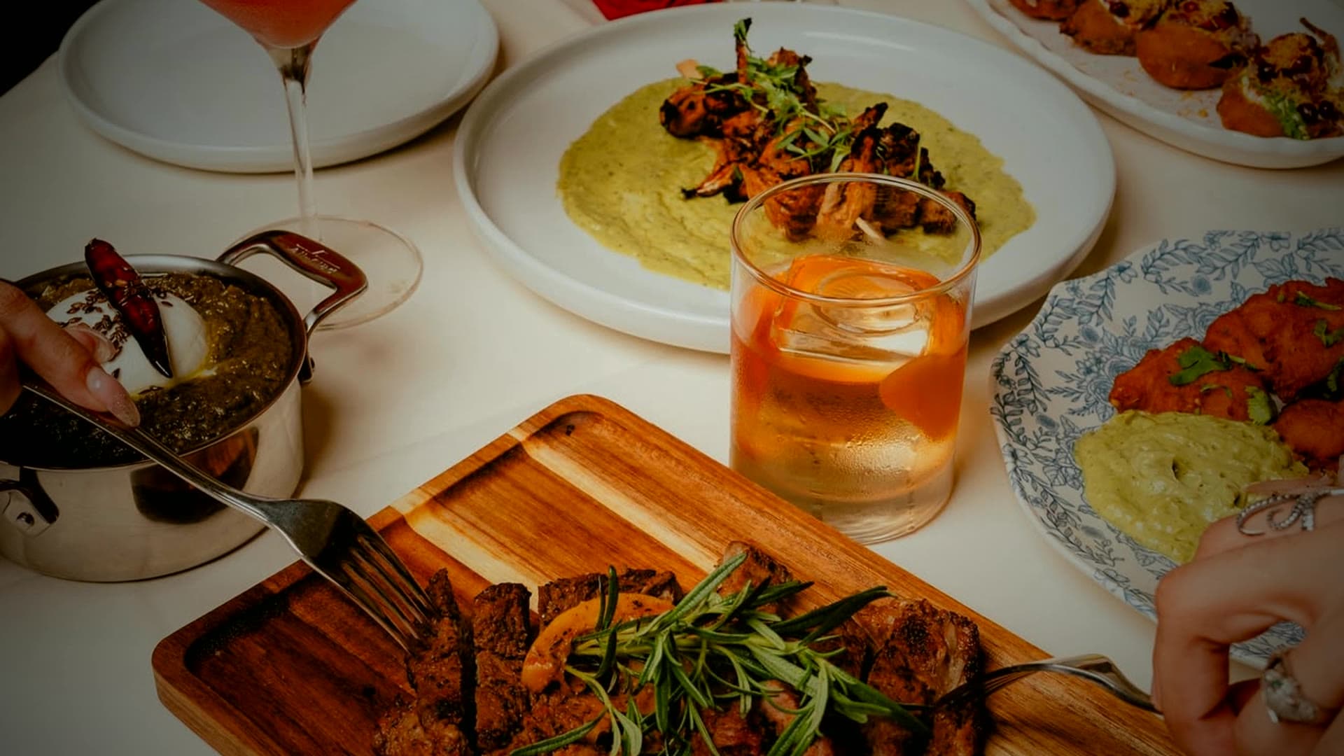 An elegant plated tablescape by Ashoka The Great — grilled kebabs, chaat, and a craft cocktail